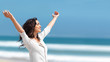 Pretty young female with arms raised standing on beach