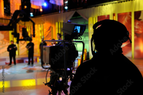 Photo: Cameraman works in the studio - recording show in TV studio Cameraman works in the studio - recording show in TV studio