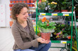 Young woman holds pot with flower in shop