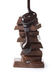chocolate syrup being poured onto chocolate pieces isolated