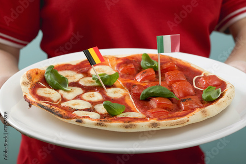 Photo: female footballer holding tomato & mozzarella pizza with flags female footballer holding tomato & mozzarella pizza with flags