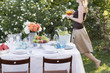 woman bringing iced tea to table laid in garden