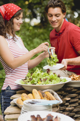Photo: young woman serving green salad at a barbecue young woman serving green salad at a barbecue