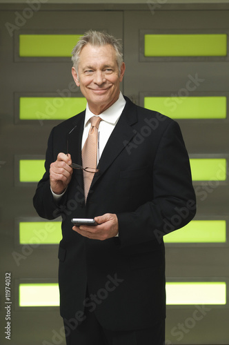 Photo: Senior Businessman Holding PDA and Glasses Senior Businessman Holding PDA and Glasses