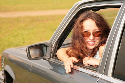 Photo: Woman smiles having turned back in a car window Woman smiles having turned back in a car window