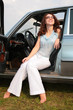 Woman sits in the car, having put bare feet on the ground