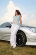 Woman stands having leant on a sport car