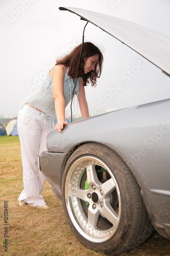 Photo: Woman looks under a car cowl Woman looks under a car cowl