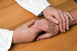 Hand einer Pflegerin und einer alten Seniorin
