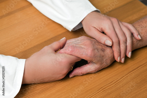 Hand einer Pflegerin und einer alten Seniorin