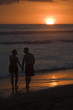Couple stroll beach at sunset