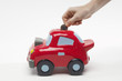 Hand Putting Money in Car Shaped Piggy Bank