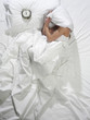 Woman in bed with alarm clock