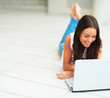 Portrait of attractive young female lying down and using laptop