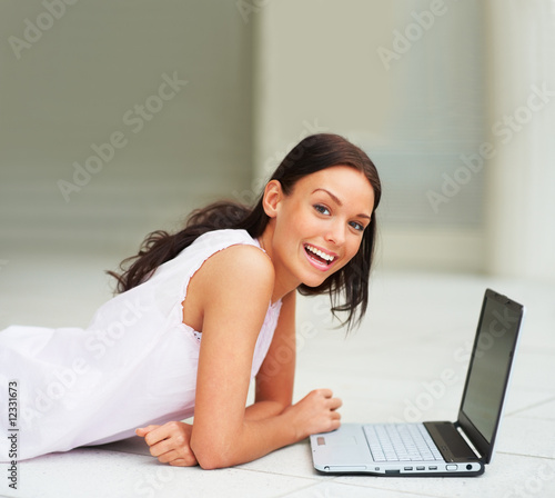 Cheerful female lying in front  with a laptop