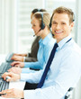 Photo: Business man working on a computer with other colleagues working Business man working on a computer with other colleagues working