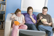 Overweight family watching television on sofa