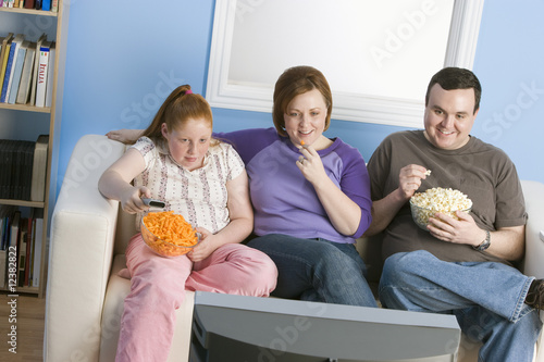 Photo: Overweight family watching television on sofa Overweight family watching television on sofa