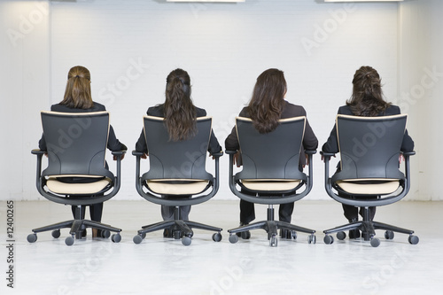 Foto: Rear view of business women sitting on office chairs. Rear view of business women sitting on office chairs.