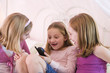 View of three cute girls looking a cellphone.