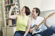 Photo: Man with guitar and woman with microphone in bedroom. Man with guitar and woman with microphone in bedroom.
