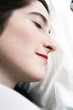 Close up of a smiling young woman resting in bed.