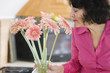 A woman smelling pink daisies.