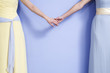 Midsection of two bridesmaids holding hands.