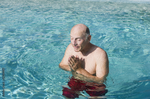 Photo: Senior man meditating in a swimming pool Senior man meditating in a swimming pool