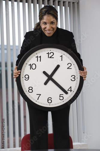 Photo: Portrait of a business woman holding wall clock. Portrait of a business woman holding wall clock.