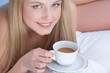 Close up of a pretty woman drinking coffee in bed