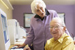 Senior woman helping senior man use computer