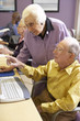 Senior woman helping senior man use computer