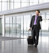 A businessman wheeling a suitcase, talking on a mobile phone
