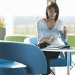 A woman sitting at a table, having a drink and writing notes