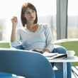 A woman sitting at a table with notes and papers, thinking
