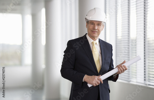 Photo: An architect wearing a hard hat holding plans An architect wearing a hard hat holding plans
