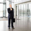 A mature businessman standing in the lobby adjusting his tie