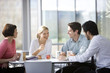 Four office colleagues eating lunch in an office canteen or cafe