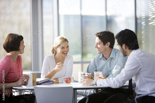 Foto: Four office colleagues eating lunch in an office canteen or cafe Four office colleagues eating lunch in an office canteen or cafe