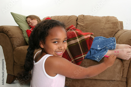 Photo: Girl playing tricks on sleeping babysitter. Girl playing tricks on sleeping babysitter.