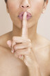 A woman holding finger to her lips, gesturing for silence