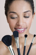 A woman holding four make-up brushes