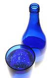 Photo: High angle view of a blue colored glass and a bottle against the white background High angle view of a blue colored glass and a bottle against the white background