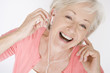 A senior woman listening to music on an mp3 player, laughing