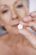 A senior woman holding a pill