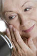 A senior woman looking at her face in the mirror
