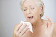 A senior woman sneezing