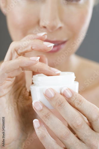 Photo: A middle-aged woman holding a pot of moisturising cream A middle-aged woman holding a pot of moisturising cream
