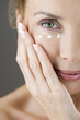 A middle-aged woman applying eye cream